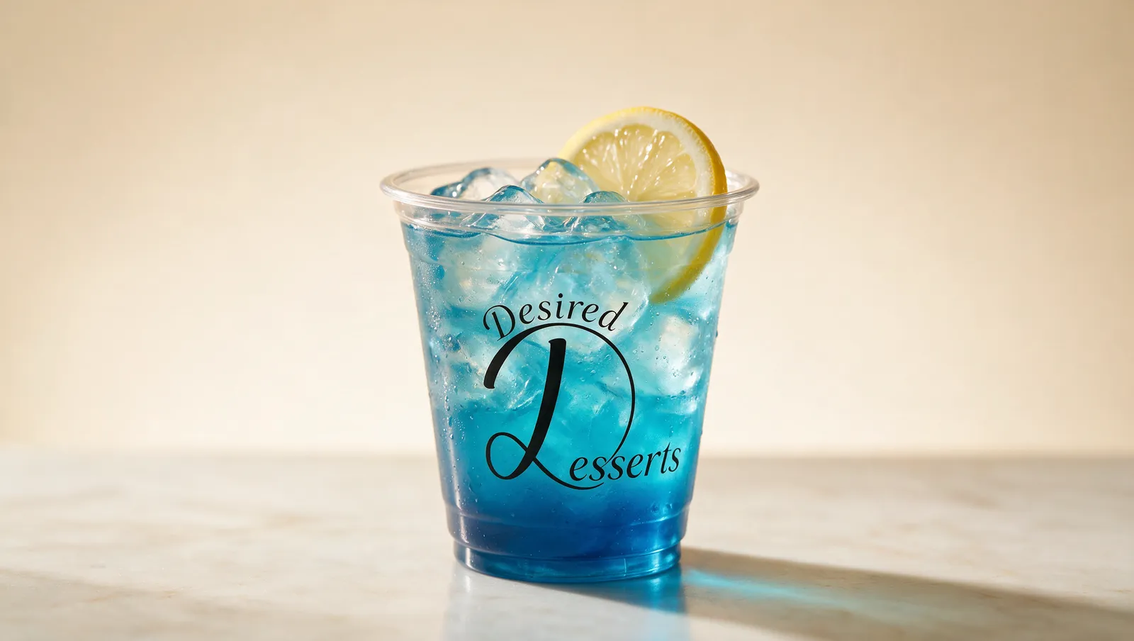 Desired Desserts Blue Bloom signature sip — vivid blue curaçao-style lemonade over ice in a clear branded cup with a lemon wheel.